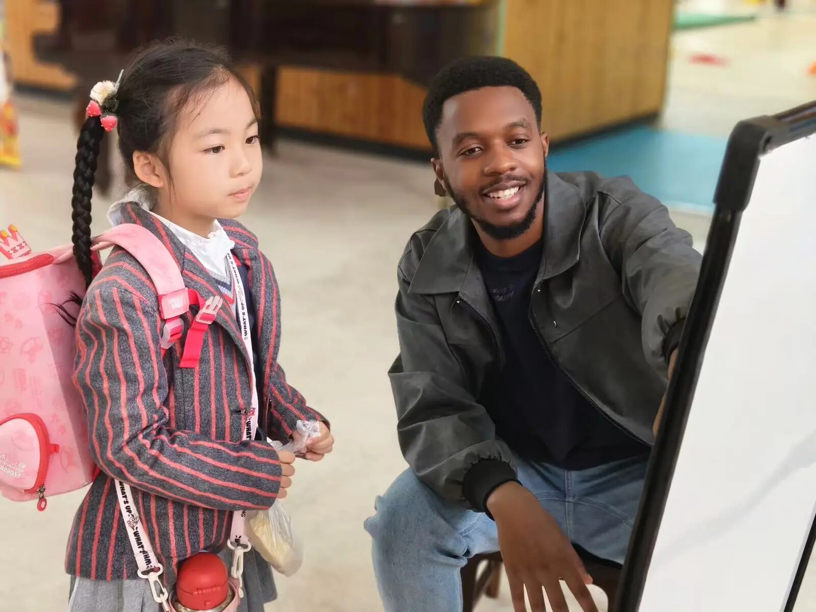 A teacher guiding a young learner during an individual speaking activity in China